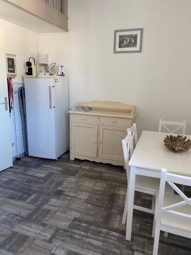 une cuisine avec un réfrigérateur blanc et une table dans l'établissement Les Remparts, à Saint-Martin-de-Ré