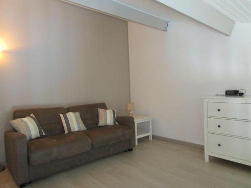 a living room with a brown couch and a dresser at Les Remparts in Saint-Martin-de-Ré