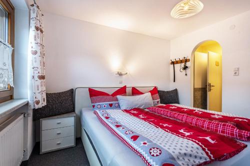 ein Schlafzimmer mit einem großen Bett mit roten und weißen Kissen in der Unterkunft Bergwelt C in Niederau