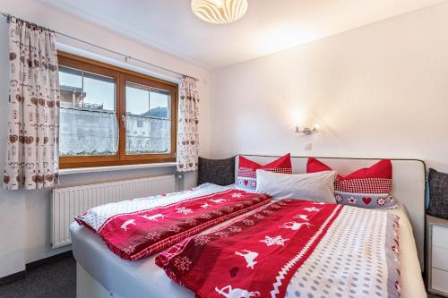 Schlafzimmer mit einem großen Bett mit roter und weißer Bettwäsche in der Unterkunft Bergwelt C in Niederau