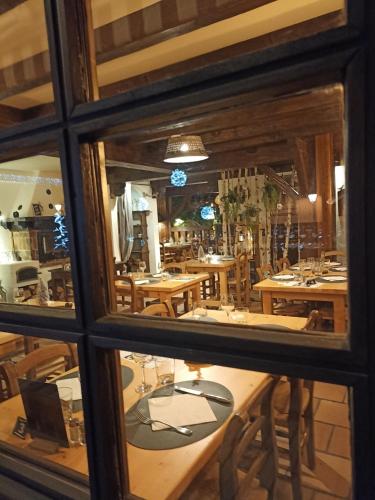 a reflection of a dining room with tables in a window at Chalet Appart'Hôtel l'Eau Vive in Saint-Nicolas-la-Chapelle