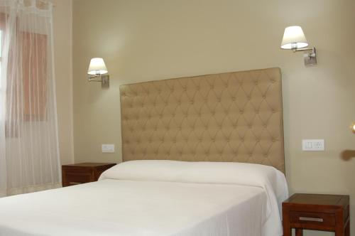 a bedroom with two beds with white sheets and two tables at Apartamentos Las Clacas in Playa Blanca