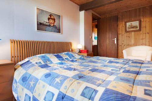 een slaapkamer met een bed met een blauwe en witte deken bij La Bergerie in Gedinne