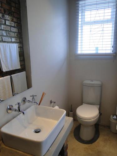 a white bathroom with a toilet and a sink at Our Nest Guest House in Kleinmond