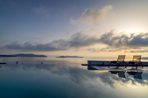 dos sillas sentadas en el borde de una piscina de agua en Luxury Villas Skiathos en Skíathos
