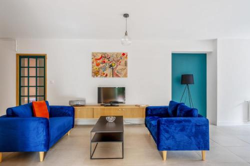 a living room with two blue chairs and a tv at Appartement Bleuet - Welkeys in Arcachon