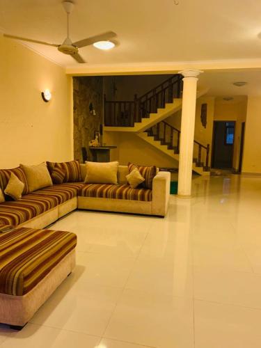 a living room with two couches and a staircase at Tharu Villa Kottawa in Pannipitiya