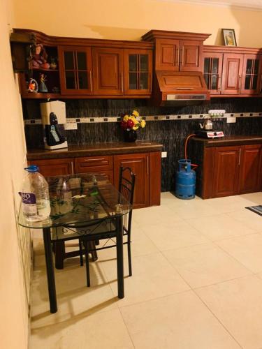 a kitchen with a glass table and wooden cabinets at Tharu Villa Kottawa in Pannipitiya