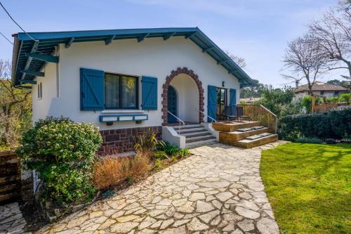 a house with blue windows and a stone driveway at Appartement Bleuet - Welkeys in Arcachon