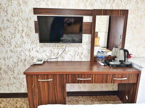 a wooden desk with a television on a wall at Rose Suite & Hotel in Buyukcekmece