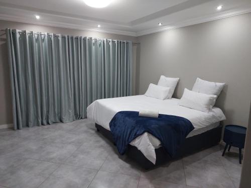 Pretoria的住宿－Alcade Ekhaya，卧室配有一张带白色床单和枕头的大床。