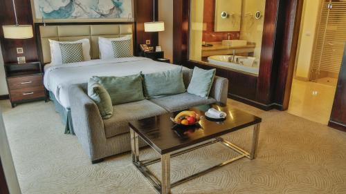 Triumph Luxury Hotel في القاهرة: غرفه فندقيه بسرير واريكه وطاولة