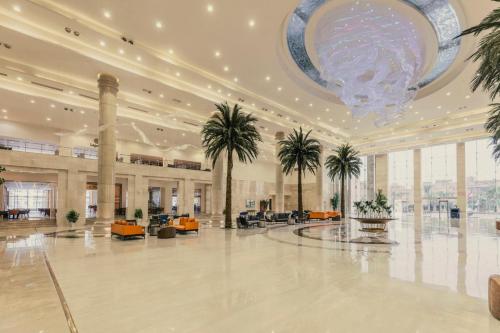 a large lobby with palm trees and a chandelier at Triumph Luxury Hotel in Cairo