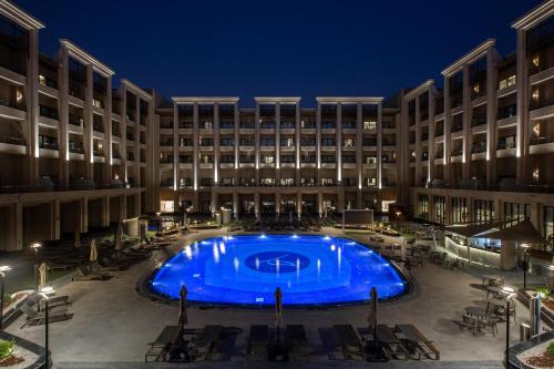 une grande piscine devant un immeuble la nuit dans l'établissement Triumph Luxury Hotel, au Caire