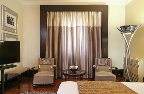 a hotel room with a bed and two chairs and a television at Hotel Britania Art Deco - Lisbon Heritage Collection - Avenida in Lisbon