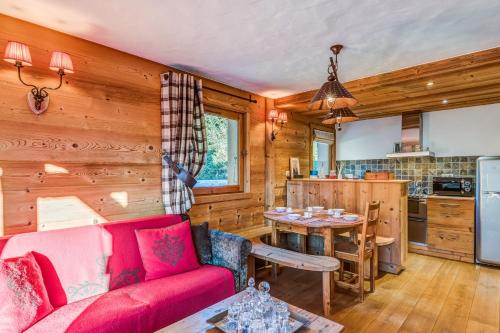 a living room with a red couch and a kitchen at Charming flat in a chalet in Megève - Welkeys in Megève