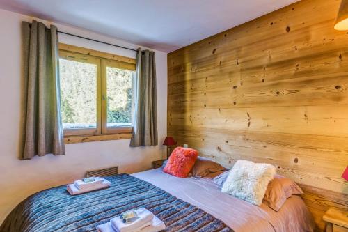 - une chambre avec un lit et un mur en bois dans l'établissement Appartement des Epis - Welkeys, à Megève