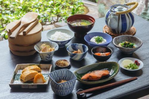 stół z miskami i talerzami jedzenia. w obiekcie Toshiharu Ryokan w mieście Kioto