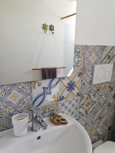 a bathroom with a sink and tiles on the wall at Alicudi Giardino dei Carrubi- al gradino 365 in Alicudi