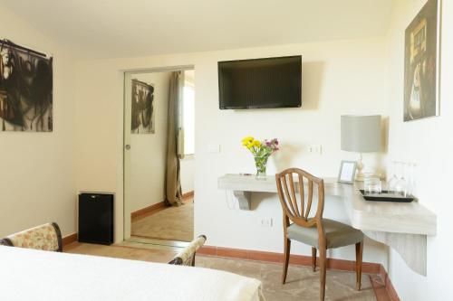 Si Montalcino Hotel في مونتالشينو: غرفة مع طاولة وتلفزيون على الحائط
