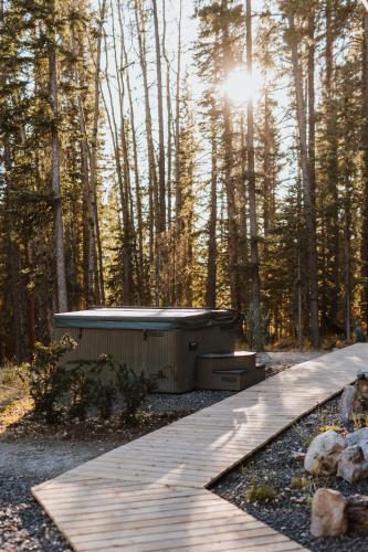 a wooden walkway with a sauna in the woods at Okt Häus in Nordegg