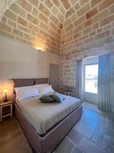 1 dormitorio con cama y pared de ladrillo en Masseria OSTUNI MARE Agri Resort, en Ostuni