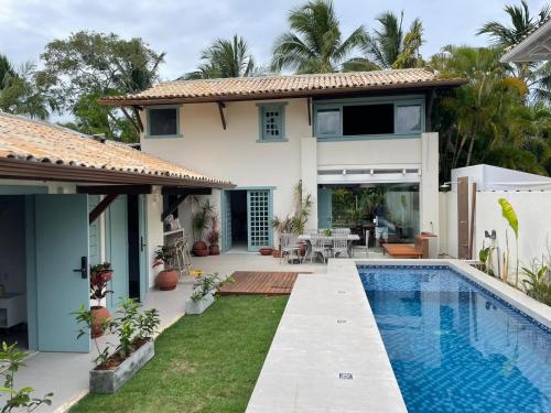 a villa with a swimming pool in front of a house at A CASA DA PRAIA DO FORTE in Praia do Forte