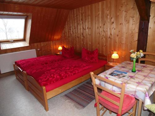 a bedroom with a red bed and a table at Doppelzimmer Oybin in Herrnhut