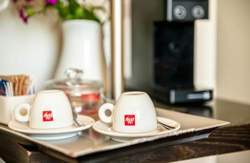 two white cups and saucers sitting on a tray at Si Montalcino Hotel in Montalcino