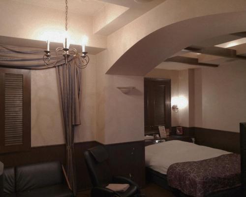um quarto de hotel com uma cama e uma cadeira num quarto em ＳＴＡＲＲＥＳＯＲＴ　Ｉ em Sayama