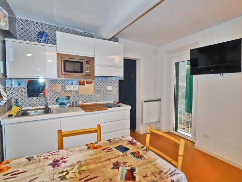 eine Küche mit weißen Schränken, einem Tisch und einem Waschbecken in der Unterkunft Casa del pescatore a 100m dal mare 011016-LT-0569 in Lerici