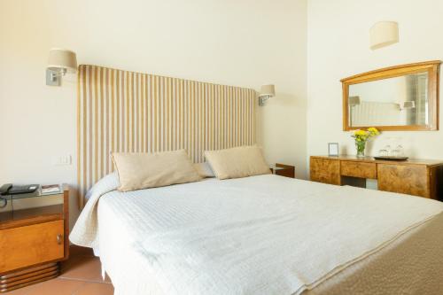 a bedroom with a white bed and a mirror at Si Montalcino Hotel in Montalcino