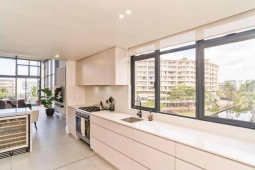 una cucina con mobili bianchi e una grande finestra di Stylish & New 4 Bedroom Point Waterfront Penthouse a Durban