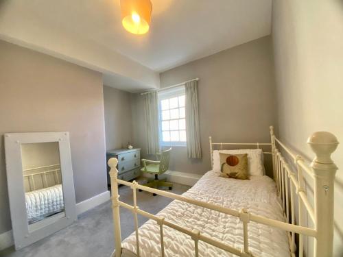 a bedroom with a white bed and a mirror at Beautiful 17th century coach house off high street in Marlborough