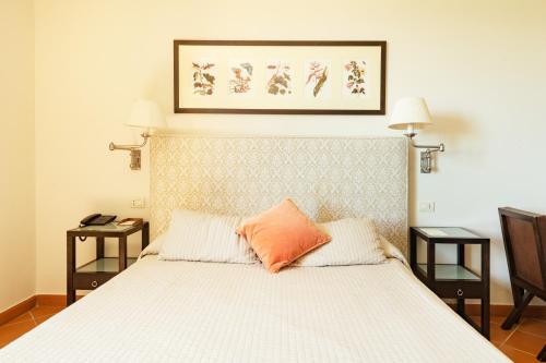 a bedroom with a bed with an orange pillow on it at Si Montalcino Hotel in Montalcino