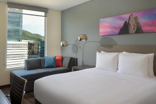 une chambre d'hôtel avec un lit, un canapé et une fenêtre dans l'établissement Hyatt House Monterrey Valle San Pedro, à Monterrey