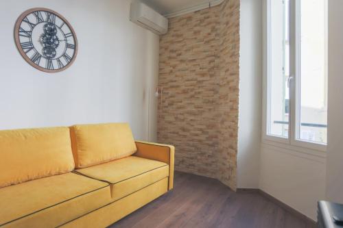 un salon avec un canapé et une horloge au mur dans l'établissement Studio Mimosa - Welkeys, à Cannes