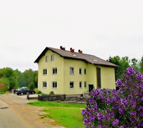 a large yellow house with purple flowers in front of it at HomeW4 - Tiny Apartment in Hoheneich