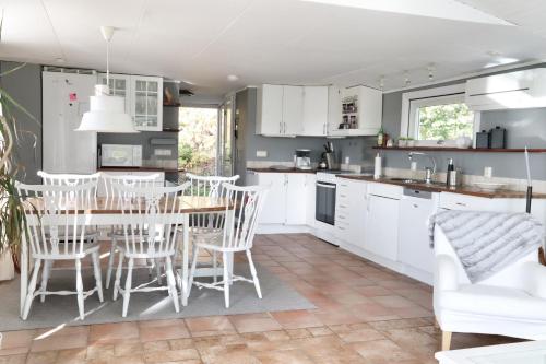 a kitchen with white cabinets and a table and chairs at Lantligt boende i idylliska Påarp in Båstad