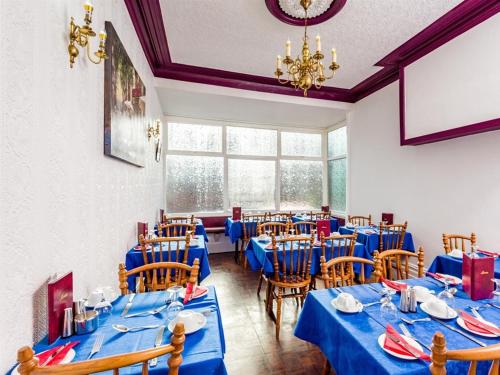a dining room with blue tables and chairs at Holmeleigh Hotel in Blackpool
