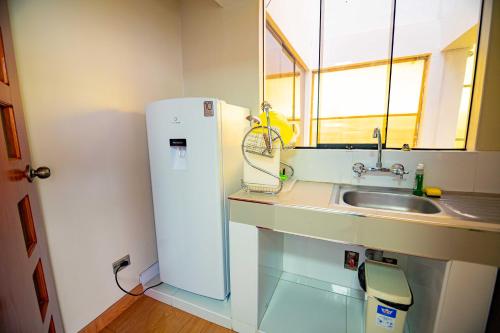 a small kitchen with a sink and a refrigerator at Departamento KIRI para familias con terraza cerca al Aeropuerto de Juliaca in Juliaca