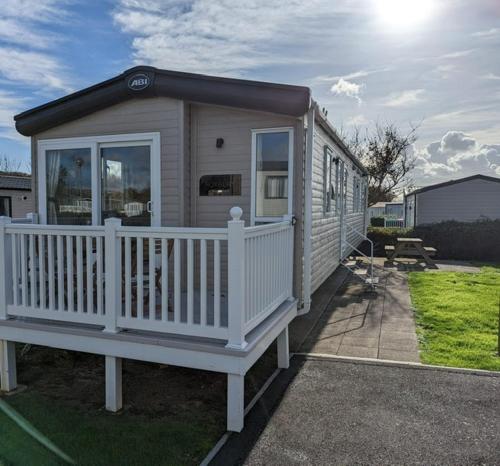 a small house with a white railing and a porch at PEACEFUL HOMELY Caravan IN LOVELY CUL DE SAC 1 DOG WELCOME ON REQUEST Littlesea Haven Weymouth in Weymouth