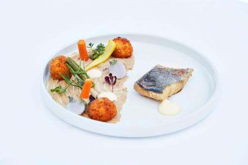 a white plate of food with meatballs and vegetables at Hôtel Château des Tourelles - Relais Thalasso & Spa in Pornichet