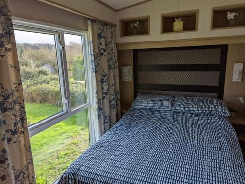 a bedroom with a bed in front of a window at PEACEFUL HOMELY Caravan IN LOVELY CUL DE SAC Littlesea Haven Weymouth in Weymouth