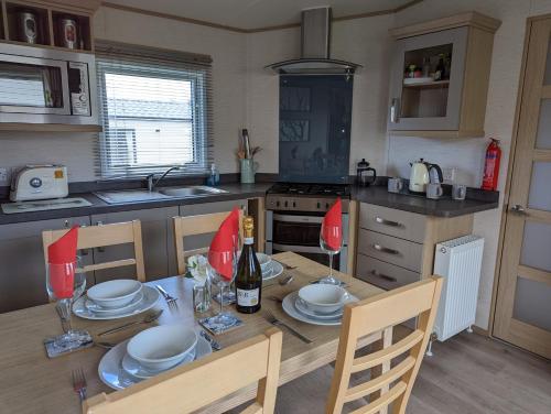 una cocina con una mesa con platos y copas de vino en PEACEFUL HOMELY Caravan IN LOVELY CUL DE SAC Littlesea Haven Weymouth en Weymouth