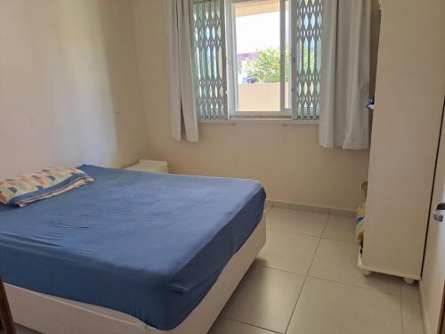 Un pequeño dormitorio con una cama azul y una ventana en Casa de Praia do Vanderlei, en Palhoça