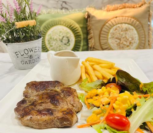 a plate of food with a steak and french fries at USABAI Riverside Boutique Hotel in Chanthaburi