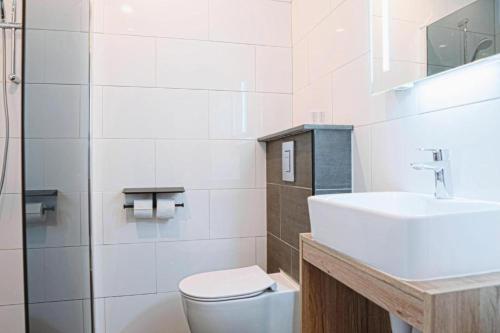 a white bathroom with a toilet and a sink at Harbour Hotel IJmuiden in IJmuiden