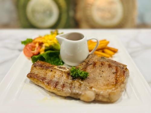 a plate of food with a piece of meat and vegetables at USABAI Riverside Boutique Hotel in Chanthaburi