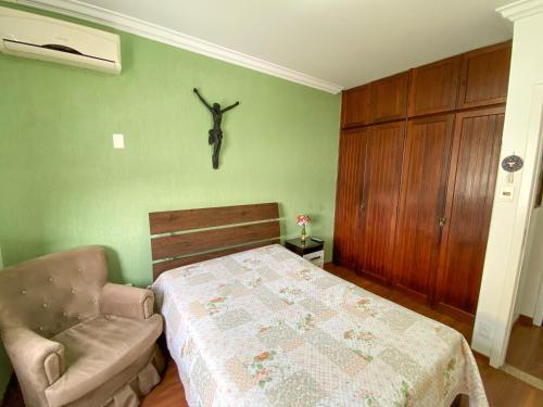 a bedroom with a bed and a chair and a skull on the wall at Elite Flat in Pará de Minas